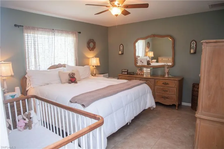 Bedroom with multiple windows, ceiling fan, and light tile patterned floors