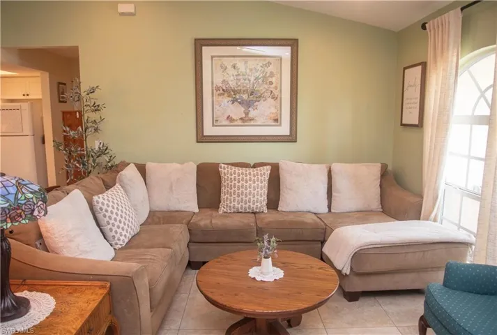 Tiled living room featuring vaulted ceiling and a wealth of natural light