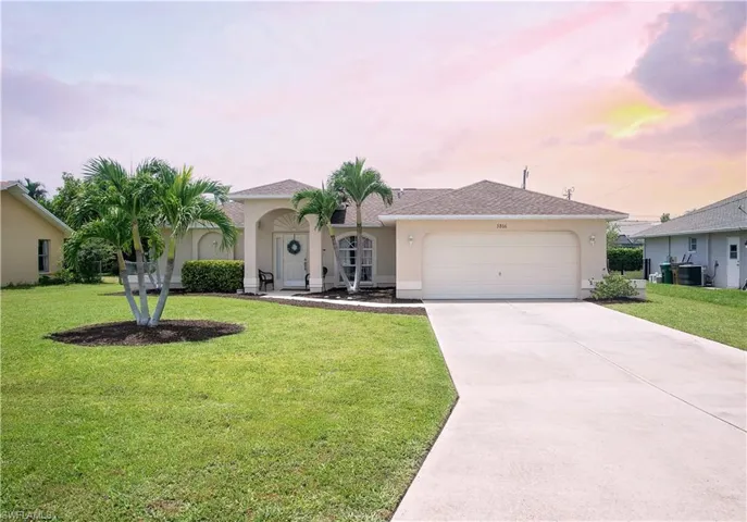 View of front of home with a garage and a yard