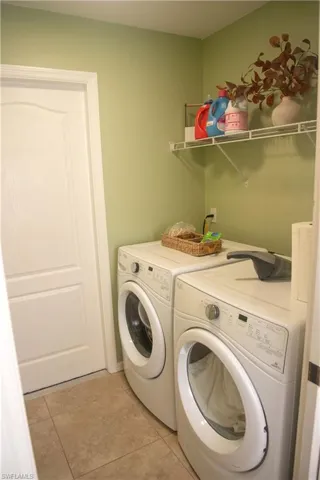 Washroom with washer and dryer and light tile patterned floors