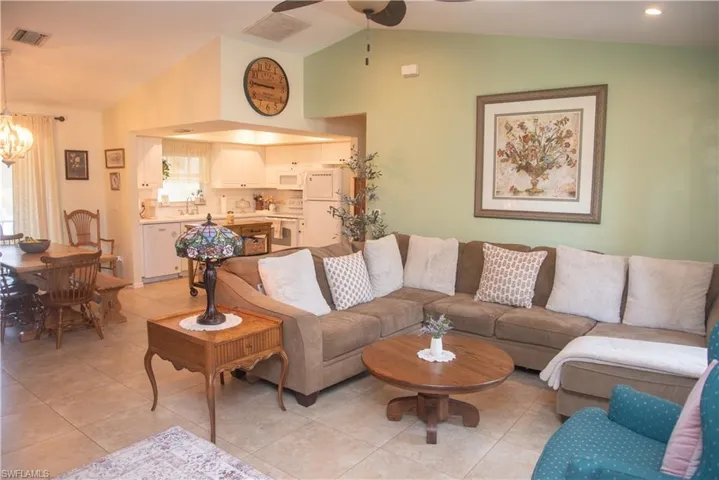 Tiled living room featuring sink, ceiling fan with notable chandelier, and lofted ceiling