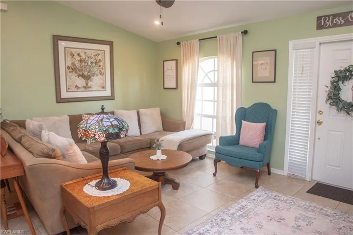 Living room featuring light tile patterned flooring and lofted ceiling