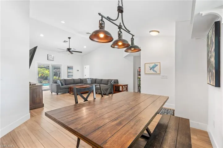 Dining space with vaulted ceiling, ceiling fan, and light wood-type flooring