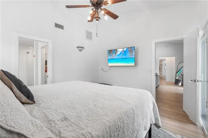 Bedroom featuring ceiling fan, a high ceiling, and light wood-type flooring