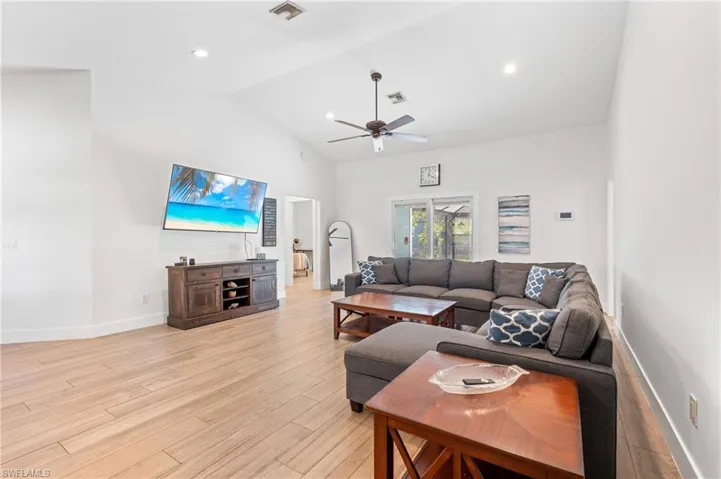 Living room with vaulted ceiling, ceiling fan, and light hardwood / wood-style flooring