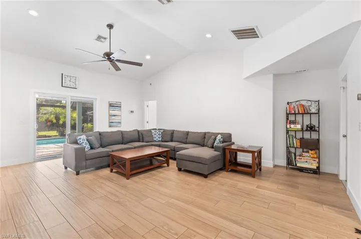 Living room with high vaulted ceiling, light hardwood / wood-style floors, and ceiling fan