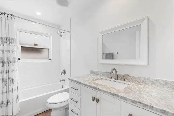 Full bathroom with vanity, wood-type flooring, toilet, and shower / bath combo