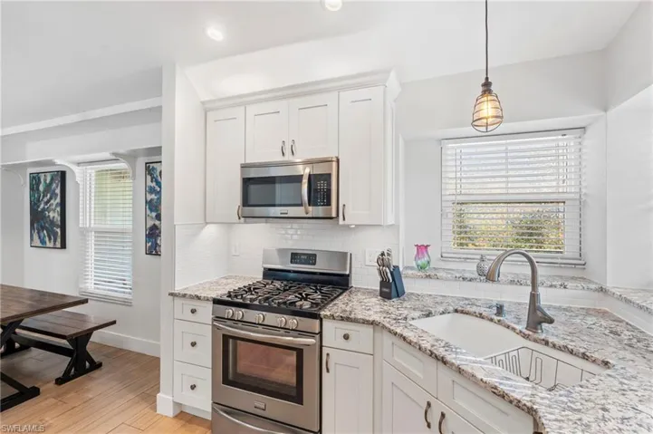 Kitchen featuring light stone countertops, appliances with stainless steel finishes, sink, and white cabinets