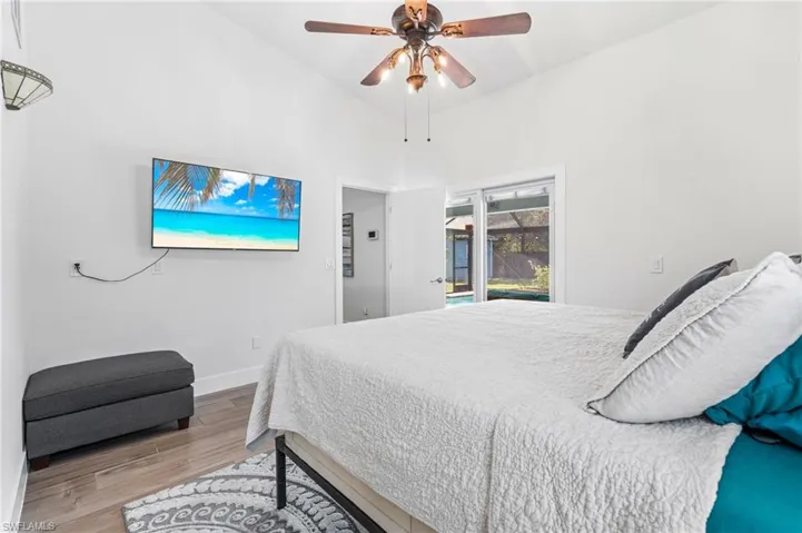 Bedroom featuring ceiling fan, access to exterior, high vaulted ceiling, and light hardwood / wood-style flooring