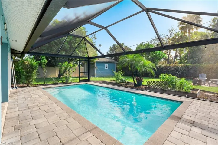 View of pool with a patio area, glass enclosure, and a storage shed