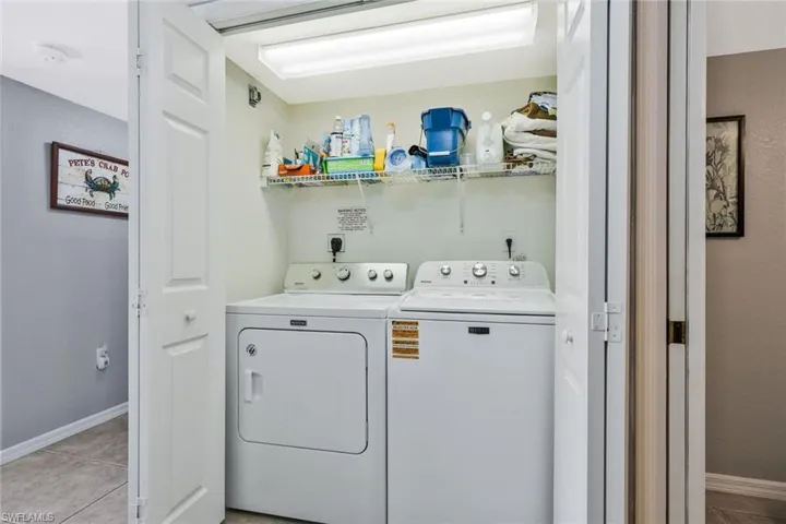 Laundry area with light tile patterned flooring and washer and clothes dryer