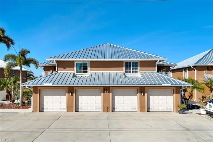 View of front of property featuring stucco siding, concrete driveway, an attached garage, and a standing seam roof