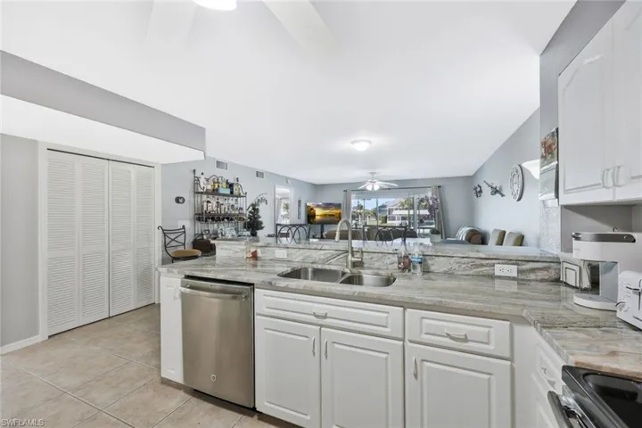 Kitchen with a ceiling fan, white cabinetry, stainless steel dishwasher, open floor plan, and black electric range