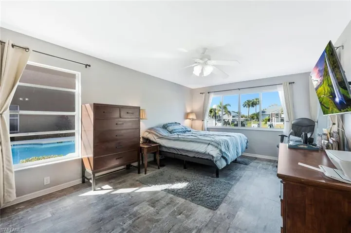 Bedroom with wood finished floors, a ceiling fan, and an office area