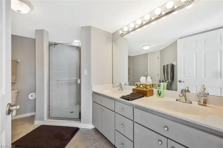 Full bath featuring double vanity, a stall shower, and light tile patterned floors