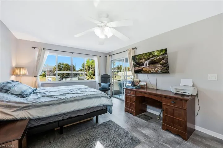 Bedroom with wood finished floors, a ceiling fan, access to exterior, and a desk