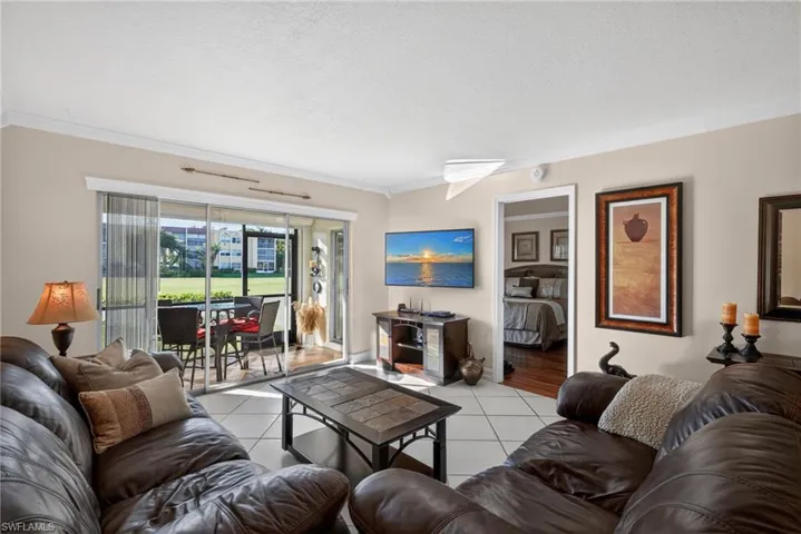 Living area featuring crown molding, light tile patterned floors, and a textured ceiling