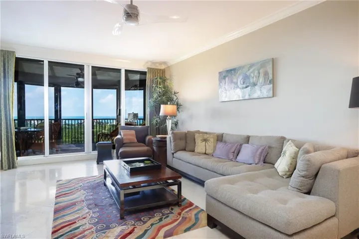 Tiled living room with a water view, ceiling fan, and crown molding