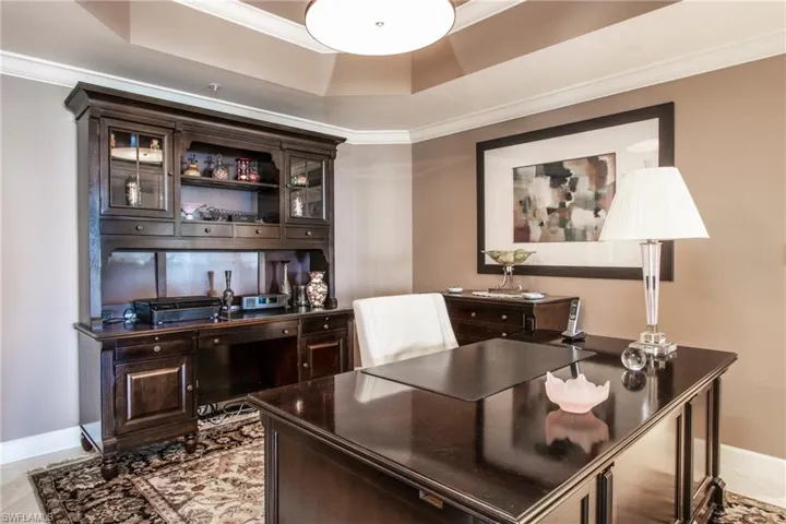 Office area with ornamental molding, light tile floors, and a raised ceiling