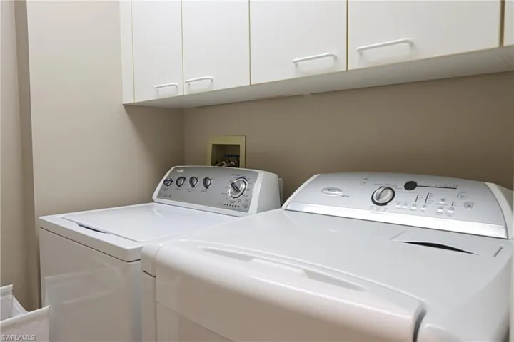 Laundry area with washer and clothes dryer, cabinets, and washer hookup
