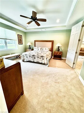 Bedroom with a tray ceiling, carpet, a ceiling fan, and crown molding