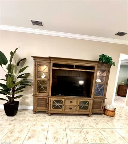 Living area with crown molding and light tile patterned floors