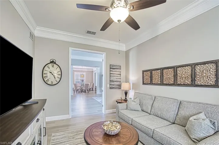 Living room with ornamental molding, light wood-type flooring, and ceiling fan