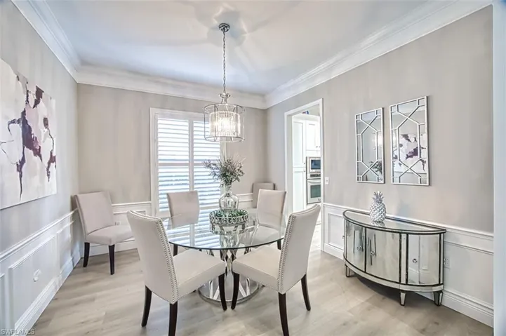 Dining space featuring light wood-type flooring, ornamental molding, and a chandelier