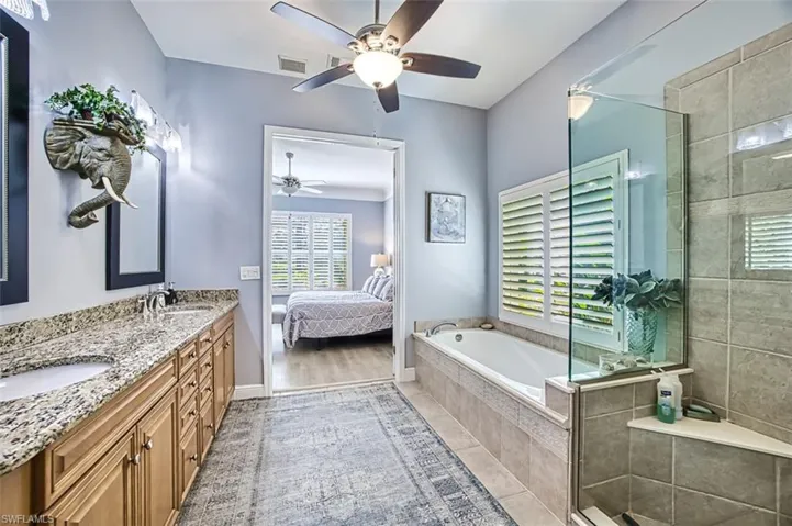 Bathroom with plus walk in shower, hardwood / wood-style floors, ceiling fan, and vanity