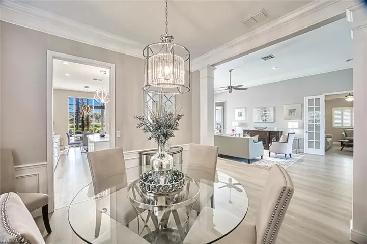 Dining room with light hardwood / wood-style floors, ceiling fan with notable chandelier, and ornamental molding