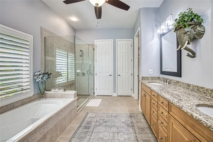 Bathroom with tile patterned floors, ceiling fan, independent shower and bath, and vanity