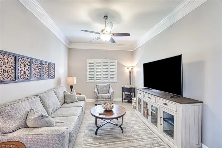 Living room featuring ceiling fan, light wood-type flooring, and ornamental molding