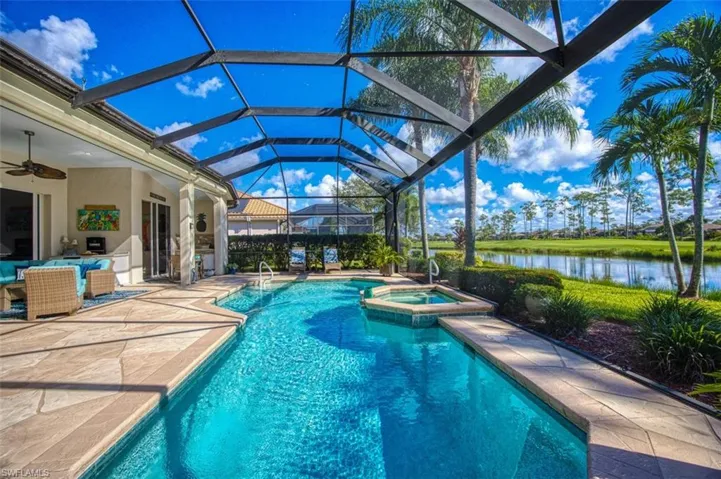 View of pool with a water view, an in ground hot tub, a lanai, ceiling fan, and a patio area