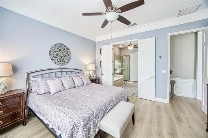 Bedroom featuring ceiling fan, light wood-type flooring, connected bathroom, and ornamental molding