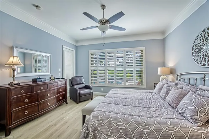 Bedroom with ornamental molding, ceiling fan, light hardwood / wood-style flooring, and a closet