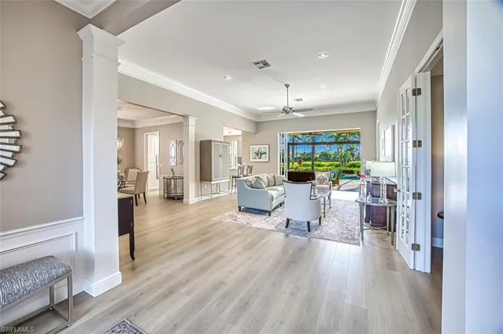 Living room with decorative columns, light hardwood / wood-style floors, ornamental molding, and ceiling fan