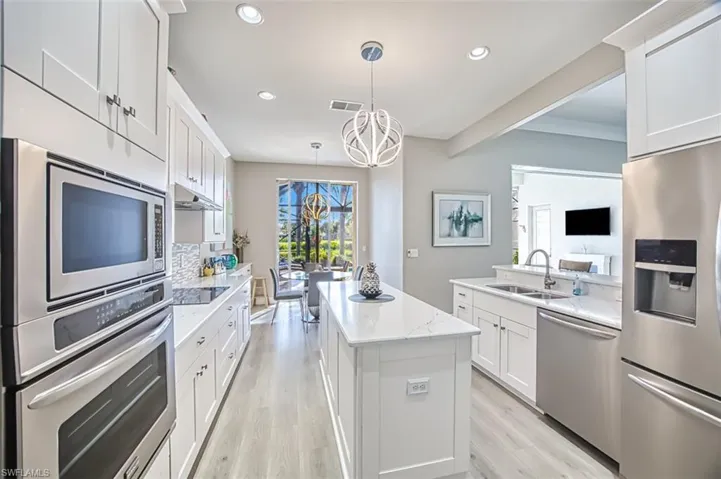 Kitchen featuring white cabinets, a kitchen island, pendant lighting, stainless steel appliances, and sink