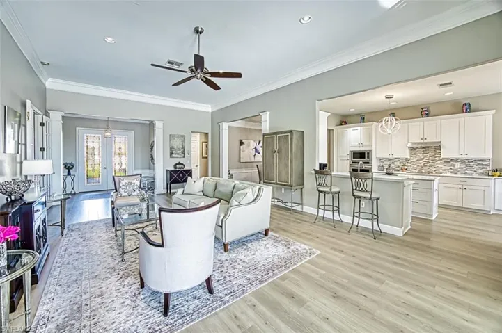 Living room with ceiling fan, crown molding, and light hardwood / wood-style floors