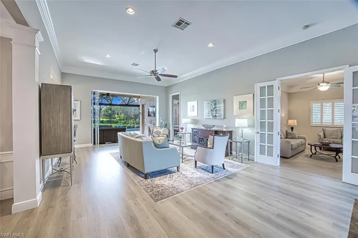 Living room featuring light hardwood / wood-style floors, ceiling fan, and crown molding