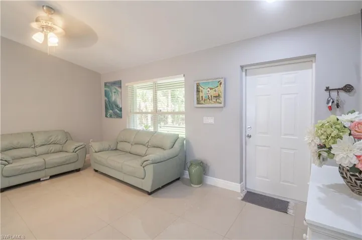 Living area featuring ceiling fan, light tile patterned floors, and baseboards