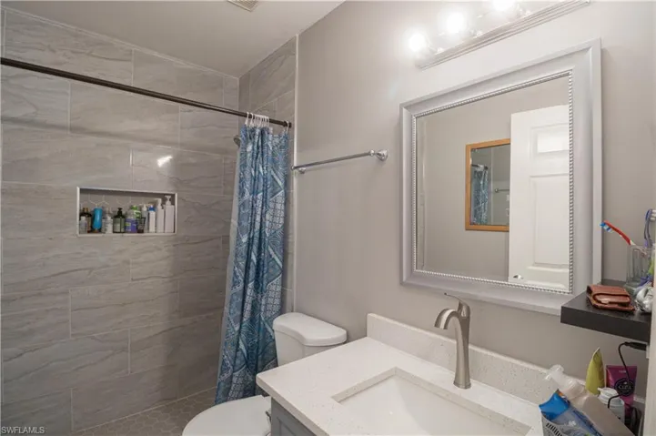 Bathroom with vanity, toilet, and tiled shower