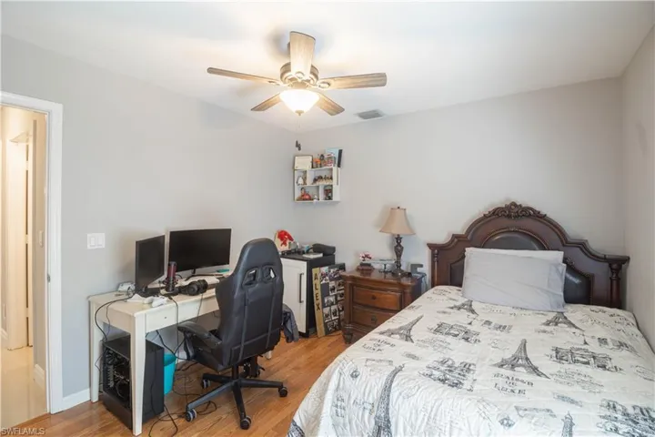 Bedroom with wood finished floors, a desk, and ceiling fan