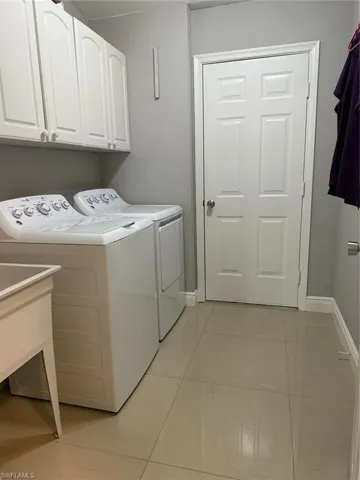 Laundry room featuring a sink, baseboards, cabinet space, and independent washer and dryer