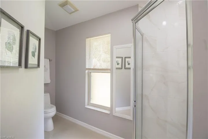 Full bathroom featuring toilet, a shower stall, healthy amount of natural light, and baseboards