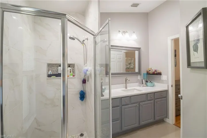 Bathroom featuring a marble finish shower and vanity