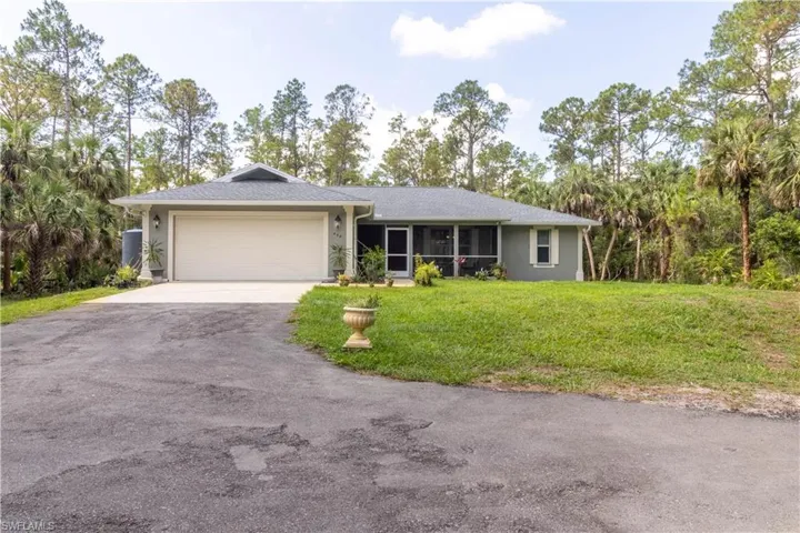 Ranch-style home with asphalt driveway, a garage, a front yard, and stucco siding