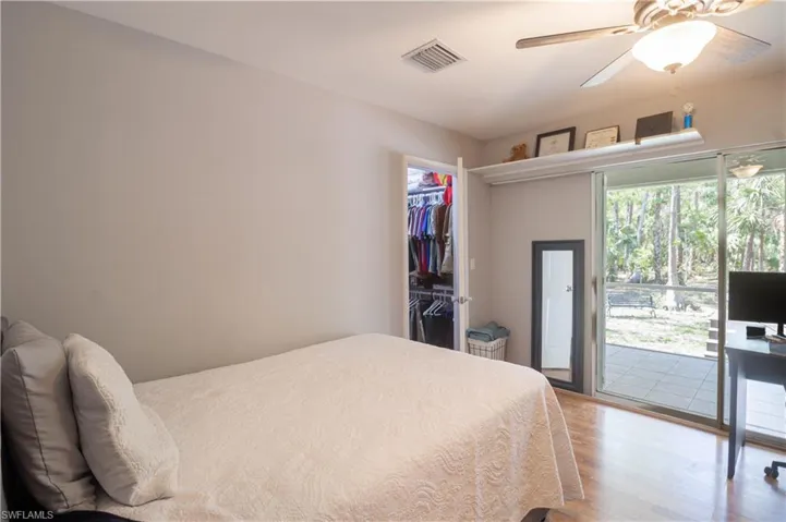 Bedroom featuring access to exterior, wood finished floors, a walk in closet, a closet, and a ceiling fan