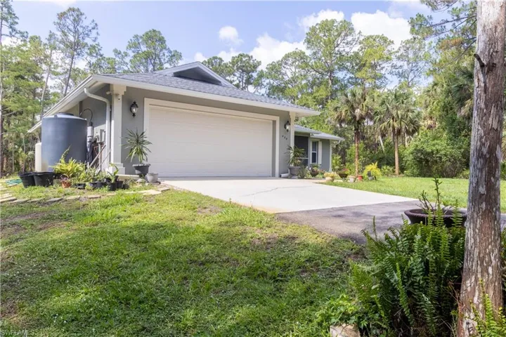 Ranch-style home featuring stucco siding, driveway, a front lawn, an attached garage, and roof with shingles