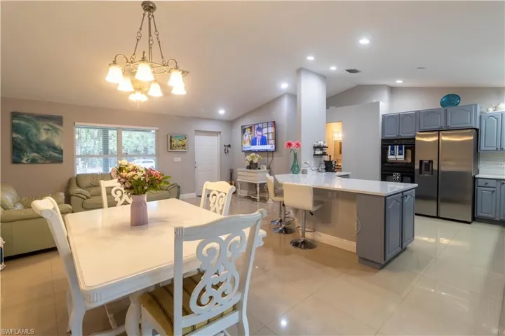 Dining space featuring lofted ceiling, a chandelier, light tile patterned flooring, and recessed lighting