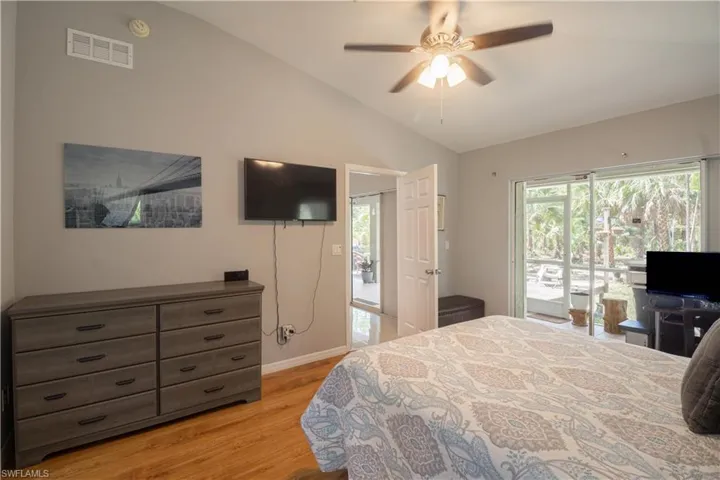Bedroom with lofted ceiling, light wood-style flooring, access to outside, multiple windows, and baseboards